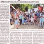 Foto von mehreren Erwachsenen und Kindern draußen vor einem Spielplatz mit bunten Ballons beim 50. Jubiläum eines Kindergartens.